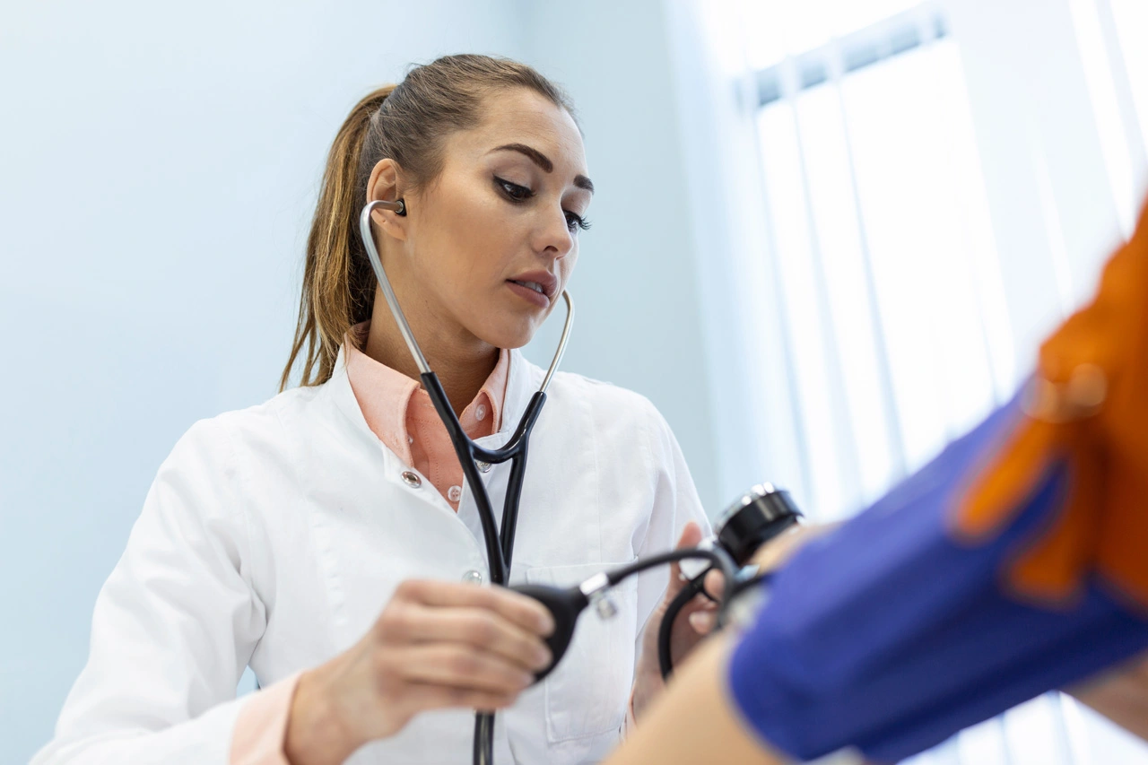 doctor-using-sphygmomanometer-with-stethoscope-checking-blood-pressure-patient-hospital